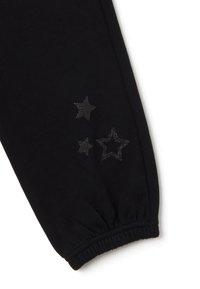 Pantalones deportivos negros con puños elásticos, hechos de tela suave, con tres diseños de estrellas brillantes estampados en el lateral.