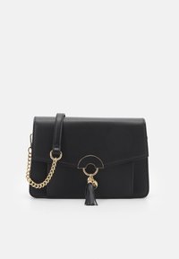 Borsa nera in ecopelle con tracolla in catena dorata, design a patta, accentuazione hardware circolare e dettaglio con nappina sul davanti.