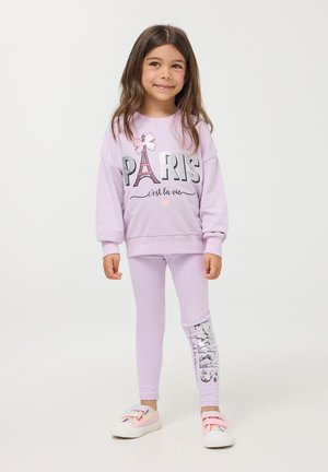 Felpa lilla con design "PARIS" e Torre Eiffel; leggings lilla abbinati con testo glitterato "PARIS" sul lato; calzature casual.