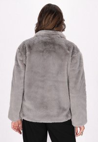 Giacca in pelliccia sintetica grigia con vestibilità comoda, caratterizzata da colletto, maniche lunghe e una texture morbida. La parte posteriore ha un aspetto liscio e uniforme.