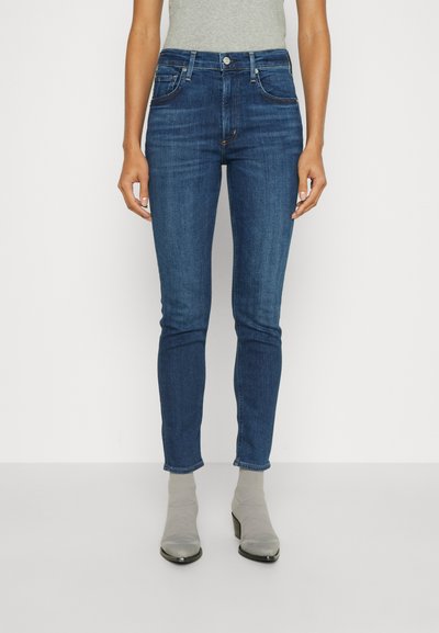 Usnjene skinny jeans v modri barvi z visokim pasom, ki imajo rahlo zbledelo barvo, pet žepov in kovinske dele na pasu.