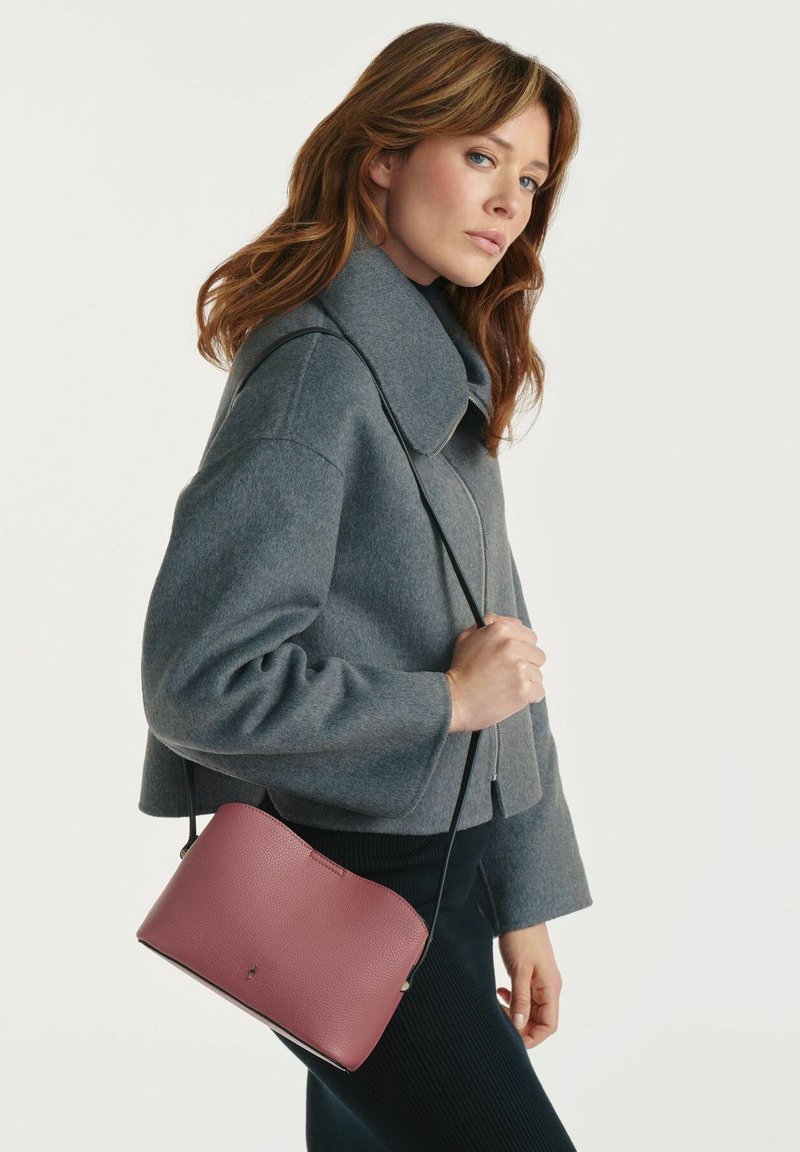Szary wełniany płaszcz z wysokim kołnierzem, w zestawie z różową torebką ze skóry o fakturze, z czarnym regulowanym paskiem.