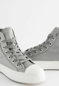 Grey high-top sneakers made of synthetic material. Features white rubber toe cap, grey eyelets, and matching laces on a thick white sole.