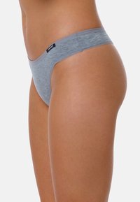 Tanga grigio in cotone con design senza cuciture e fascia sottile in vita, caratterizzato da un piccolo etichetta nera con logo sul davanti. Tessuto morbido e liscio.