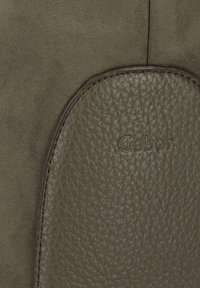 Olijfgroene handtas met een gladde leren accent en een gestructureerde suede afwerking. Bevat een reliëflogo en contrasterende stiksels.