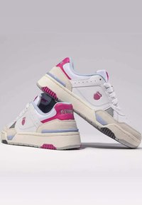 Sneaker bianche con dettagli rosa, pannelli testurizzati e suola solida. Presentano un logo sul lato e marchio sul tallone. Design spesso e imbottito.