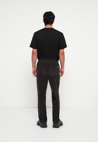 Black short-sleeve t-shirt and dark corduroy pants, featuring elastic waistband and two back pockets, worn with black chunky sneakers.