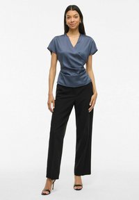 Haut à style enveloppant en satin navy avec des manches courtes, associé à un pantalon large noir. La tenue présente des lignes épurées et une texture lisse.