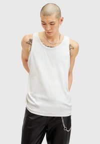 Witte mouwloze tanktop met een ronde halslijn, voorzien van een zachte textuur en een comfortabele pasvorm. Gecombineerd met slanke zwarte broeken met kettingdetails.