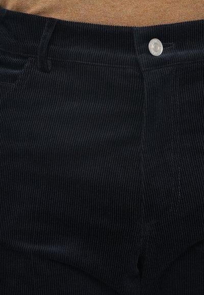 Schwarze Baumwollcordhosen mit vertikaler Rippstruktur, einem silbernen Knopfverschluss und klassischen Taschen an der Taille, mit einer weichen Textur.