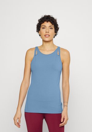 Top de tiras azul justo, com recortes nos ombros, feito de tecido suave. Combinado com leggings bordeaux, com costuras mínimas visíveis.