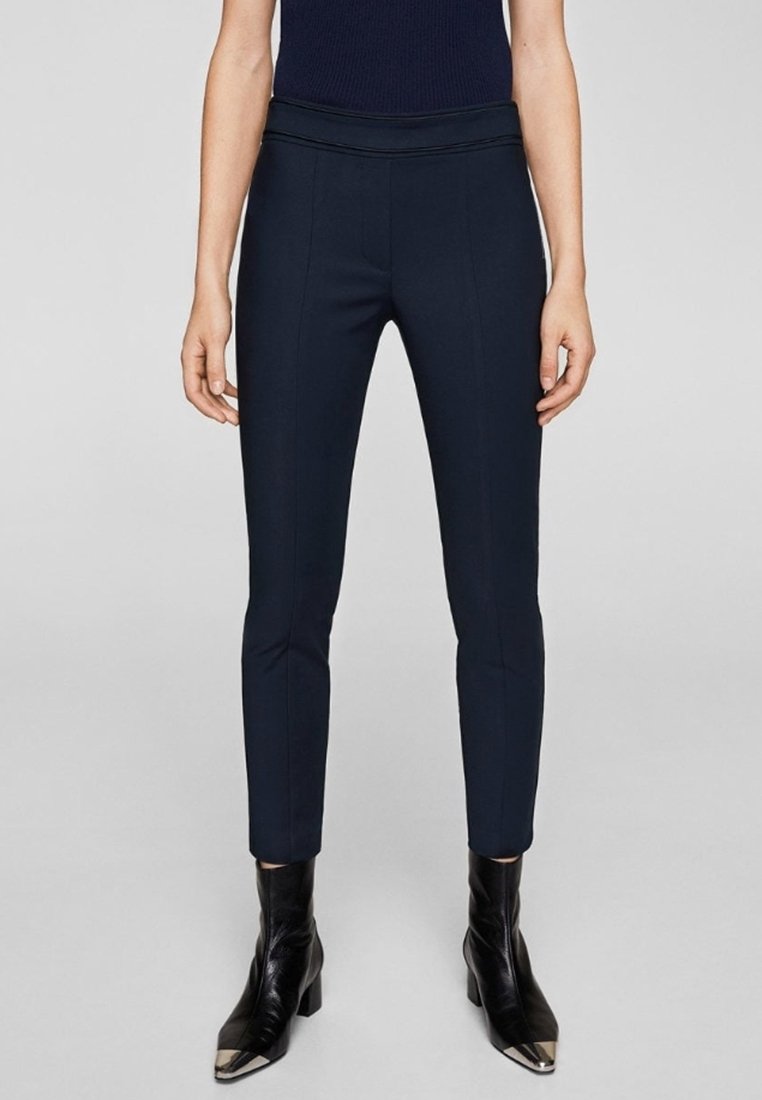 Marineblauwe broek met een aansluitend ontwerp, een gladde textuur en een hoge taille. Gecombineerd met zwarte enkellaarsjes met metallic neuzen.