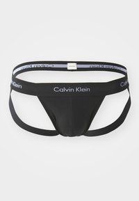 Schwarzer Calvin Klein Tanga mit einem Stoffvorderteil und elastischen Bändern. Verfügt über einen mit Logo versehenen Bund in Weiß und Grau. Minimalistisches Design.