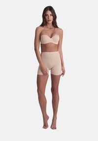 Nude strapless beha en high-waisted shorts gemaakt van een soepele stof. De set heeft een naadloos ontwerp en een neutrale kleur.