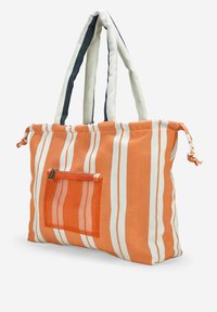 Bolso tote a rayas en tela naranja y blanca, con un bolsillo de malla y asas de dos colores. Diseño estructurado con cierre de cordón.