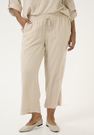 Beige linnen broek met een elastische tailleband en koord. Kenmerken zijn een cropped lengte en zijzakken. Gemaakt om te dragen met lichte, platte schoenen.