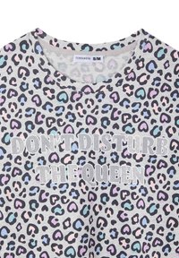 Maglietta grigia a maniche corte con un motivo leopardato in cuori neri, rosa e blu; con il testo "NON DISTURBARE LA REGINA" in argento.