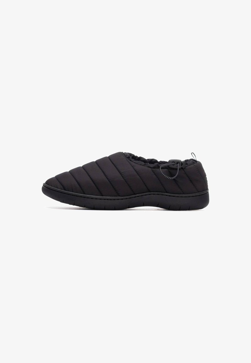 Zapato negro de tipo slip-on acolchado con cuello elástico, punta redonda y suela de goma texturizada. Presenta un diseño minimalista y un toggle ajustable.