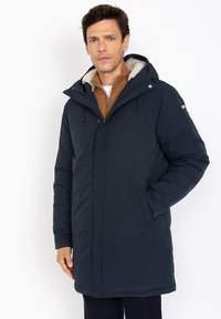 Parka acolchada de color azul marino con capucha, que cuenta con un forro cálido, bolsillos frontales y cierre de cremallera. Textura suave y tejido resistente a las inclemencias del tiempo.
