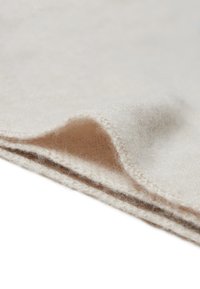 Helles beiges Wollgewebe mit einer weichen, flauschigen Textur, das eine gefaltete Kante und dezente Nähte aufweist.