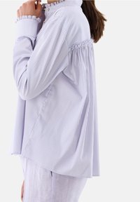 Blusa a righe blu e bianche con scollo e maniche a volant, con una vestibilità oversize e una texture di tessuto morbido.