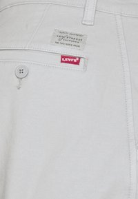 Lichtgrijze denimspijkerbroek met knoopsluiting aan de voorkant. Voorzien van een rode Levi's-logo tag en een geweven label met merkdetails aan de achterkant.