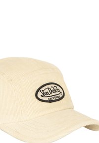 Cappellino in corduroy beige con un patch ovale nero che riporta la scritta "Von Dutch" e "California". Visiera curva e dettagli in tessuto testurizzato.