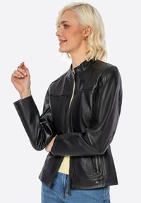 Giacca in pelle nera dal design elegante, con colletto alto, zip frontale, tasche laterali e dettagli di cucitura sulle spalle.