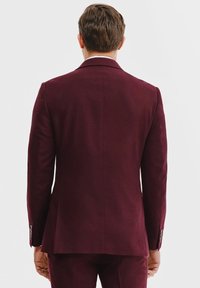 Bordowa marynarka o dopasowanym kroju, z klapami i mankietami na trzy guziki. Wykonana z teksturowanej tkaniny, prezentuje czyste linie i dopasowany design.