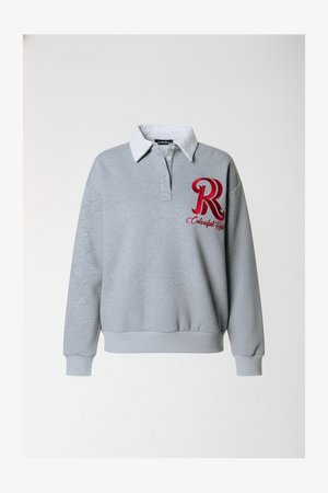 Grå sweatshirt med en hvid krave, prydet med et rødt broderet "R"-logo. Lange ærmer med ribstrikkede manchetter og kant. Blødt bomuldsmateriale.