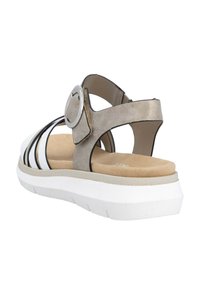 Open-toe sandal with a metallic gold upper, black accents, and circular buckle. Features a white platform sole with textured beige insole.