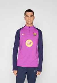 Camisola de mangas longas com um corpo roxo e mangas azuis marinhas, com um logótipo amarelo do Spotify e o emblema do Barcelona na frente. Gola com fecho éclair.