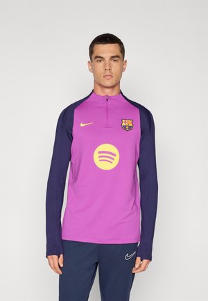 Maillot à manches longues avec un corps violet et des manches bleu marine, arborant un logo Spotify jaune et le blason de Barcelone à l'avant. Col zippé.