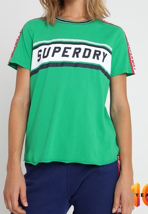 Grøn t-shirt med korte ærmer og "SUPERDRY"-tryk i hvid og marineblå, med røde accenter på ærmerne og en afslappet pasform.