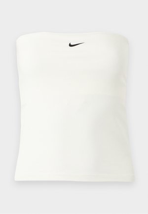 Bela Nike cevljenka brez naramnic z rdečim logotipom Swoosh, ki je nameščen na sredini blizu zgornjega roba, prikazana na enostavni lahki podlagi.
