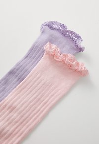 Kniestrümpfe in Helllila und Pink, mit gerippter Textur und Spitzenbesatz an der Oberseite. Jeder Strumpf hat ein einzigartiges Blockdesign in verschiedenen Farben.
