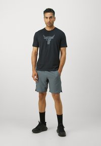 Black t-shirt with a bull graphic, paired with gray athletic shorts. The outfit features a relaxed fit and is completed with black socks and shoes.