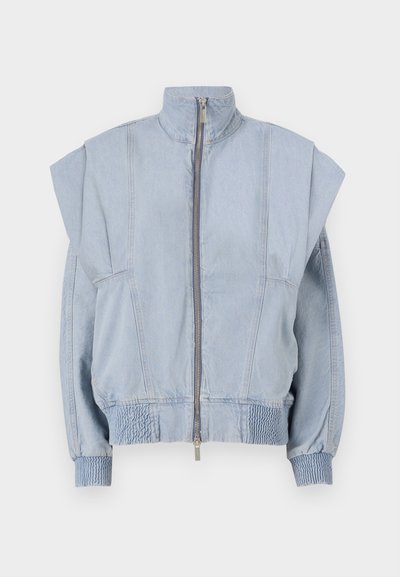 Helehelesin sinine džinnjak, millel on kõrge krae, lukuga sulgemine ja laiad õlad. Omab kogutud mansette ja smock-normi taljet, mis tagab sobiva istuvuse.