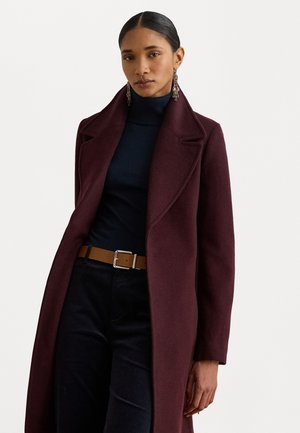 Garšs bordo mētis ar izgriezumu, izgatavots no tekstūras auduma. Valkāts pāri tumši zila turtleneckam, kombinēts ar gaiši brūnu jostu un tumšām biksēm.