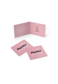 Eine pinkfarbene gefaltete Karte mit einer handschriftlichen Nachricht im Inneren. Zwei zusätzliche pinkfarbene Karten zeigen "Danke" in fettem Schwarztext, mit gestalterischen Akzenten.