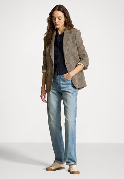 Brown houndstooth blazer, navy ribbed shirt, light blue jeans, and beige sneakers. Blazer has a tailored fit and rolled sleeves.