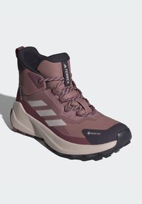 GORE-TEX žygio batai melsvai purpurinės ir smėlio spalvos, su aukšta kulkšnimi, tekstūruota viršutine dalimi, atspindinčiomis juostelėmis ir tvirtu juodu guminiu padu.
