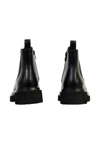 Bottes chelsea en cuir noir à la conception épurée, dotées d'une semelle épaisse et d'une languette à l'arrière pour un enfilage facile.