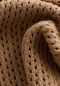 Knit fabric in brown with an openwork pattern featuring small holes, creating a textured and layered appearance. Soft, fuzzy finish.