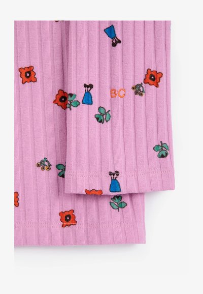 Tissu rose côtelé avec de petites fleurs rouges brodées, des feuilles vertes, des robes bleues et des initiales orange "BC" sur le bas de l'ourlet.