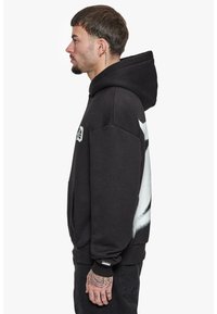 Schwarzer Kapuzenpullover mit einer frontalen Kängurutasche, ausgestattet mit auffälligen weißen grafischen Details an der Seite und gerippten Bündchen am Saum.
