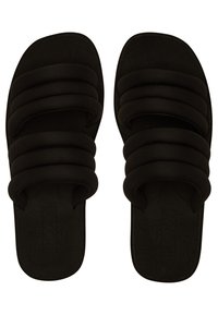Mustad mustad sandaalid, millel on kolm paksu kangast rihma ja tekstureeritud jalatuge, millel on peenet lilledemuster. Roxy logo on valmistatud tallale.