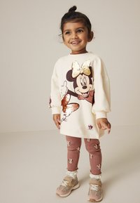 Minnie Mouse'i teemaline kreemivärvi sviiter, millel on sädelev sall, koos roosa jalgpükstega, millel on küüliku muster, ja roosade tossudega.