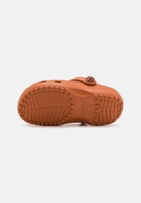 Talpa de pantof de cauciuc portocalie cu un model texturat pentru aderență, având un accent cu un logo circular și găuri de drenaj pentru ventilație.