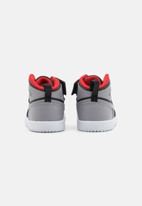 Sneaker alte grigie con fodera in rete rossa, dettagli neri e due strap in velcro. Suole in gomma bianca con battistrada testurizzato.